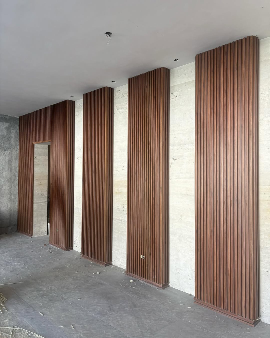 Floor-to-ceiling wood column cladding with vertical slat profiles
